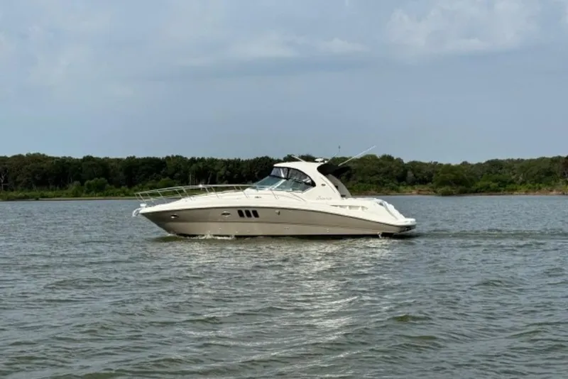 Slide: The Image of 2006 Sea Ray 38 Sundancer cruising on a calm lake with forested shoreline. - 49