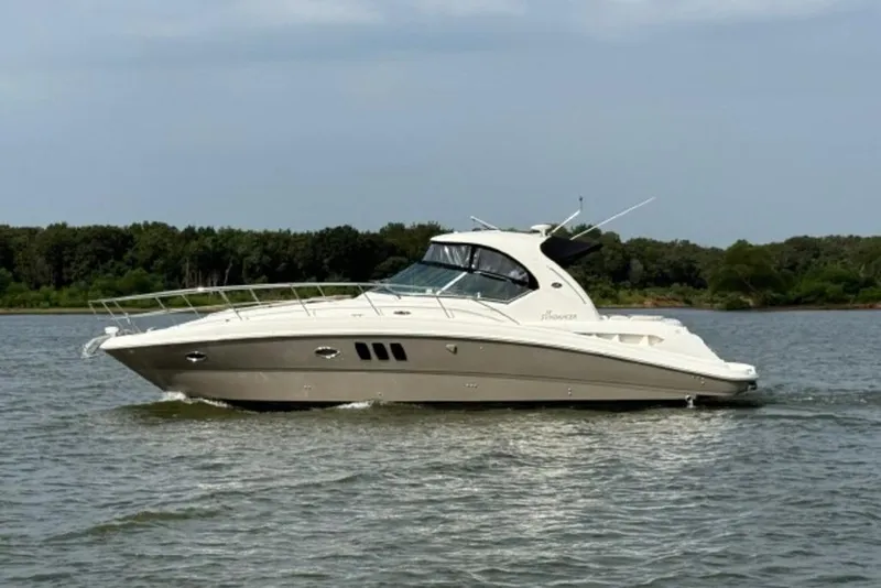 Slide: The Image of 2006 Sea Ray 38 Sundancer yacht cruising on a calm lake with forested shoreline. - 52