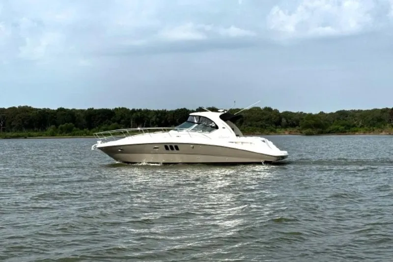 Slide: The Image of 2006 Sea Ray 38 Sundancer cruising on a calm lake with forested shoreline. - 8