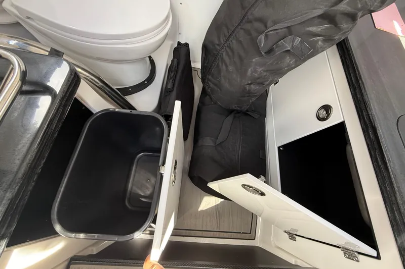 Slide: The Image of Interior storage compartments of 2026 Monterey 27 SD Elite boat, featuring a trash bin and cabinet. - 19