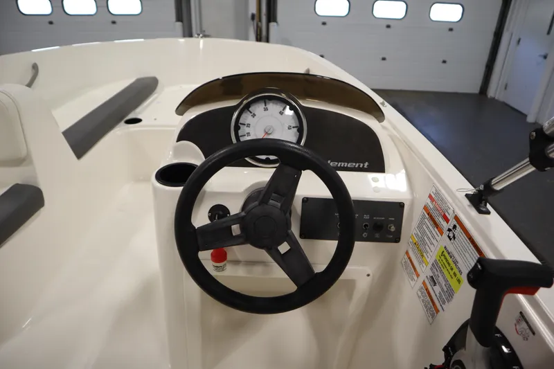 Slide: The Image of 2021 Bayliner 16 Element boat dashboard with steering wheel and gauges in a garage setting. - 16