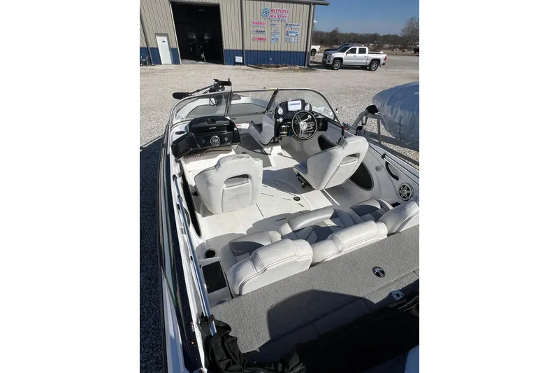 Slide: The Image of 2020 Nitro Z19 Sport boat interior with seating and steering wheel, parked outdoors. - 13