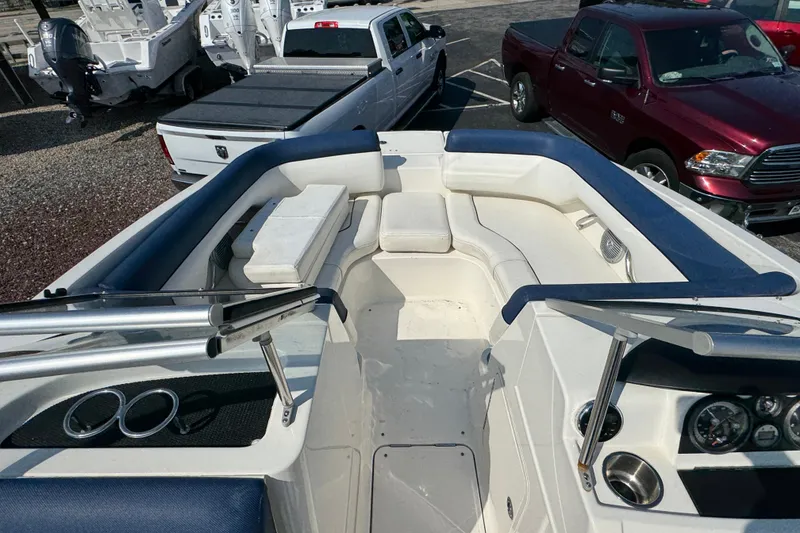 Slide: The Image of 2015 Bayliner 190 Deck Boat interior with seating, parked near trucks. - 13