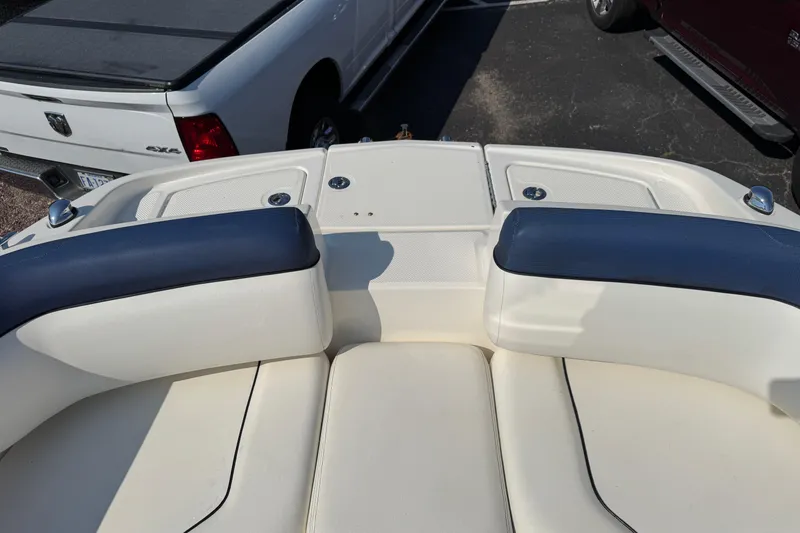 Slide: The Image of 2015 Bayliner 190 Deck Boat interior with blue and white seating, parked near a truck. - 16