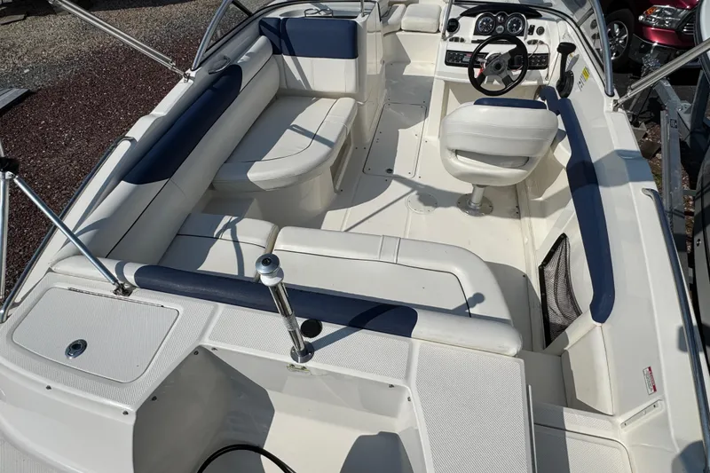 Slide: The Image of 2015 Bayliner 190 Deck Boat interior with white seating and steering console. - 5