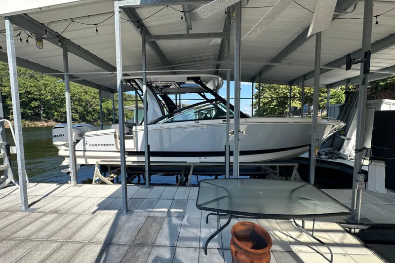 Slide: The Image of 2020 Chaparral 300 OSX boat docked under a covered marina with Yamaha engines. - 0
