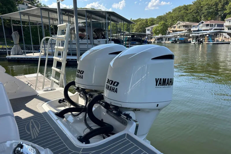Slide: The Image of 2020 Chaparral 300 OSX boat with twin Yamaha 300 engines docked by a lakeside. - 12