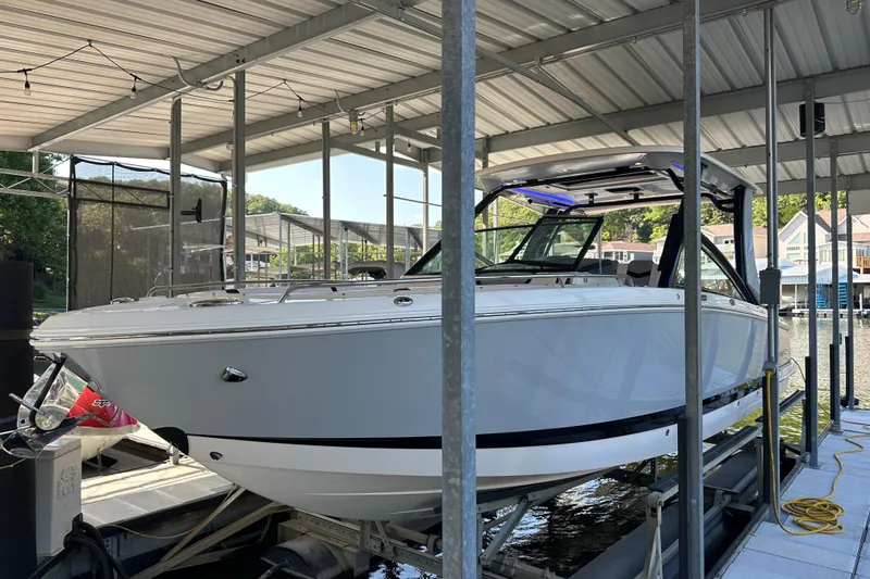 Slide: The Image of 2020 Chaparral 300 OSX boat docked under a covered marina. - 15