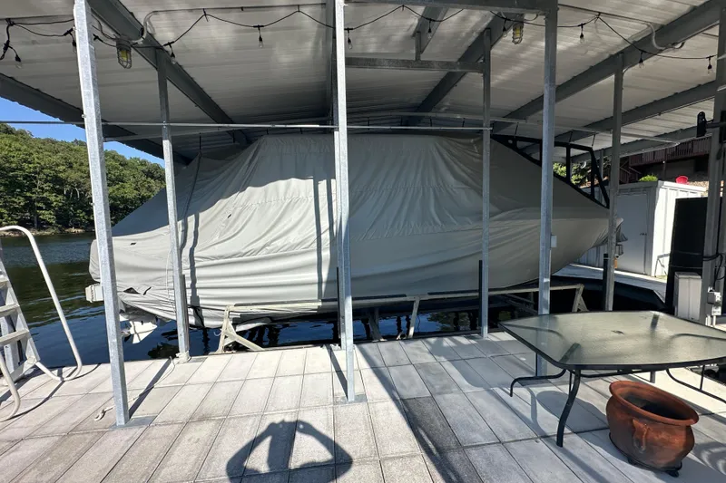 Slide: The Image of Covered 2020 Chaparral 300 OSX boat docked under a metal canopy. - 18