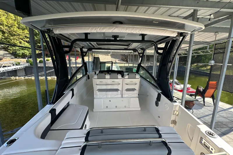 Slide: The Image of 2020 Chaparral 300 OSX boat interior with seating and storage under a covered dock. - 20