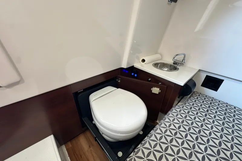 Slide: The Image of 2020 Chaparral 300 OSX boat bathroom with toilet, sink, and patterned flooring. - 45