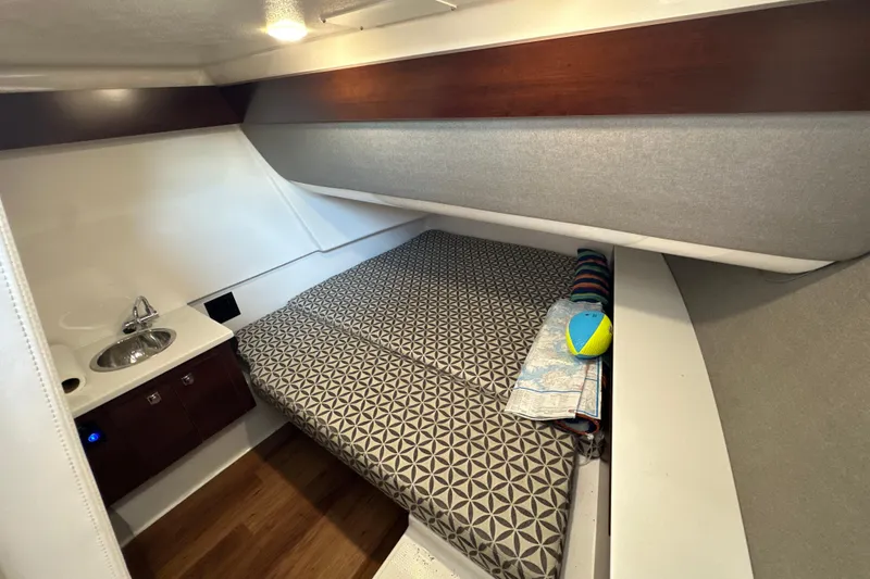 Slide: The Image of 2020 Chaparral 300 OSX cabin interior with bed, sink, and map. - 46