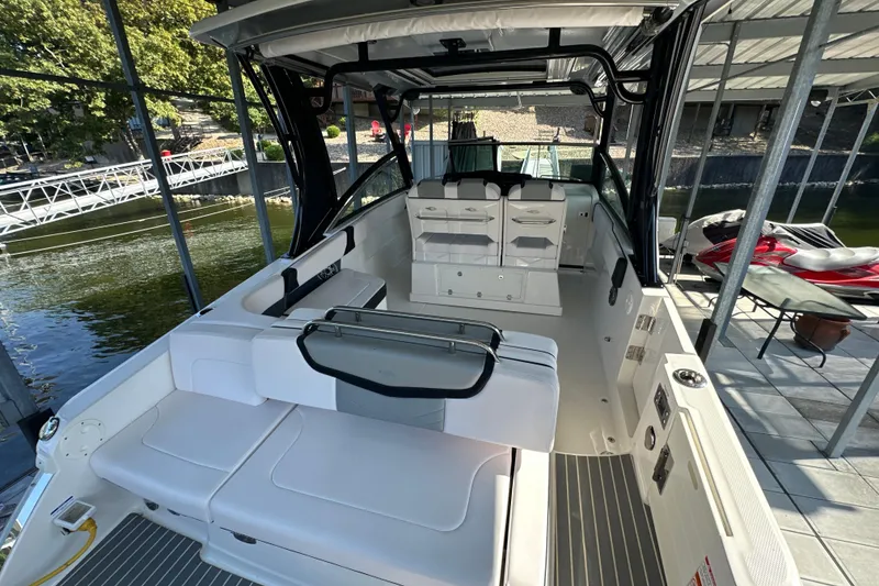 Slide: The Image of 2020 Chaparral 300 OSX boat interior, featuring sleek seating and modern design in a marina setting. - 49