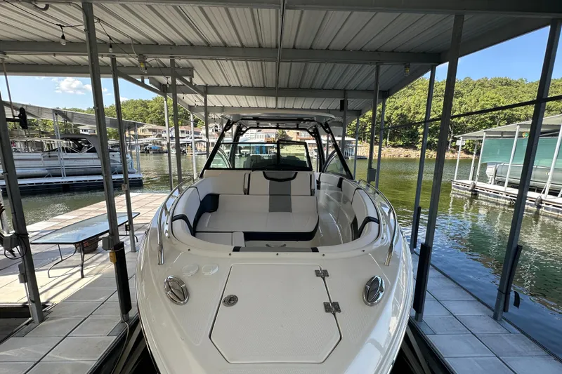 Slide: The Image of 2020 Chaparral 300 OSX boat docked in a covered marina with scenic lake view. - 9