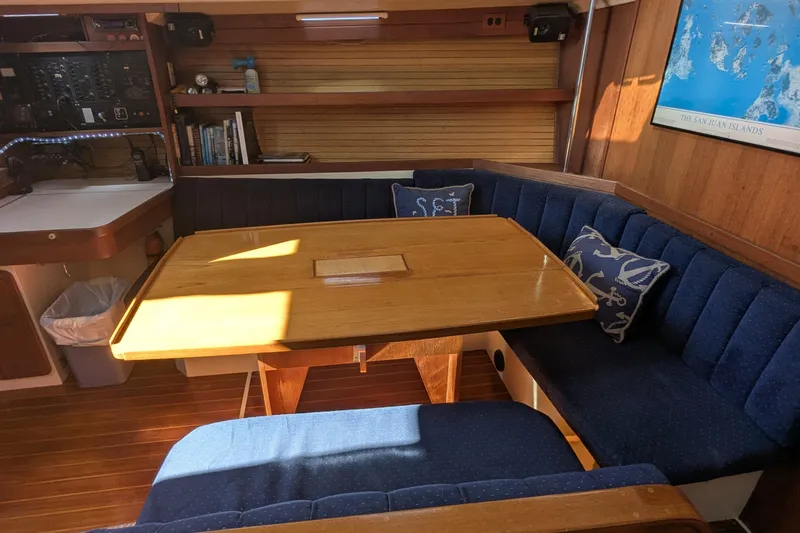 Slide: The Image of Interior of a 1990 Catalina 42 sailboat with wooden table and blue cushioned seating. - 13