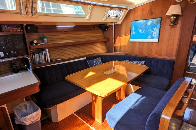Slide: The Image of Cozy interior of a 1990 Catalina 42 sailboat with wooden table and blue seating. - 14