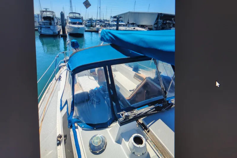 Slide: The Image of 1990 Catalina 42 sailboat docked in marina, featuring blue canopy and clear windows. - 6