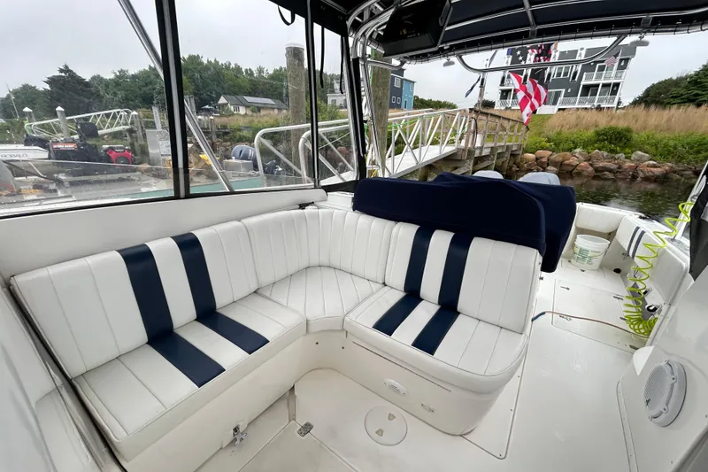 Slide: The Image of 2003 Intrepid 310 Walkaround boat with white and navy seating, docked near a marina. - 4