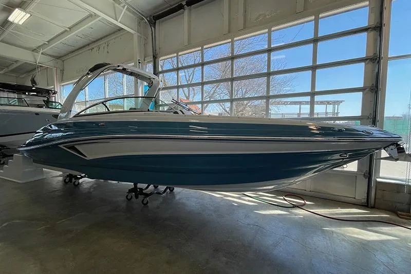 The Image of 2024 Crownline 290SS boat in showroom, side view, blue and white design. - 1