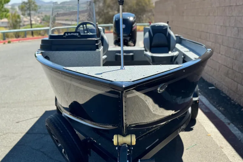 Slide: The Image of 2024 Lund 1775 Adventure Sport boat, black exterior, parked on a sunny day. - 2
