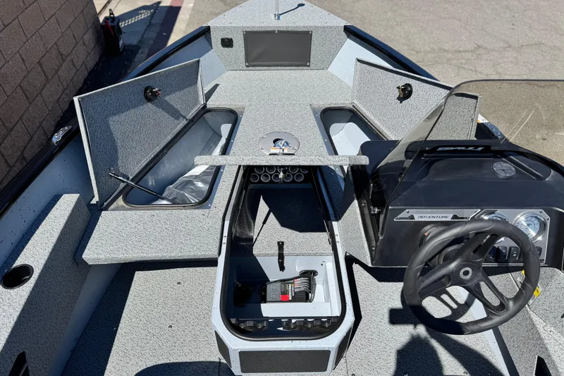 Slide: The Image of 2024 Lund 1775 Adventure Sport boat interior with open storage compartments and steering console. - 8