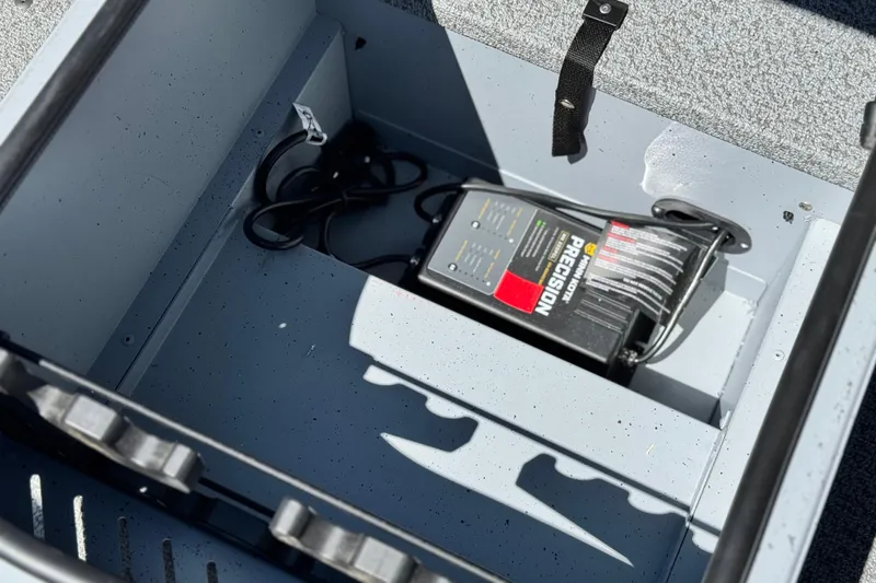 Slide: The Image of 2024 Lund 1775 Adventure Sport boat compartment with battery charger and cables. - 9