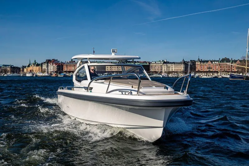 Slide: The Image of 2023 Nimbus W9 boat cruising on a sunny day with cityscape in the background. - 10