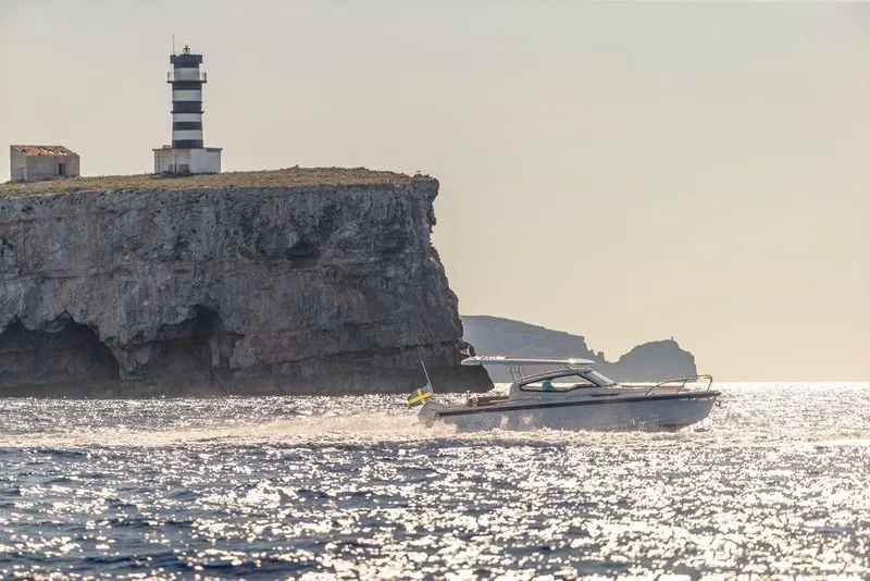 Slide: The Image of 2023 Nimbus W9 boat cruising near rocky cliff with lighthouse in the background. - 17