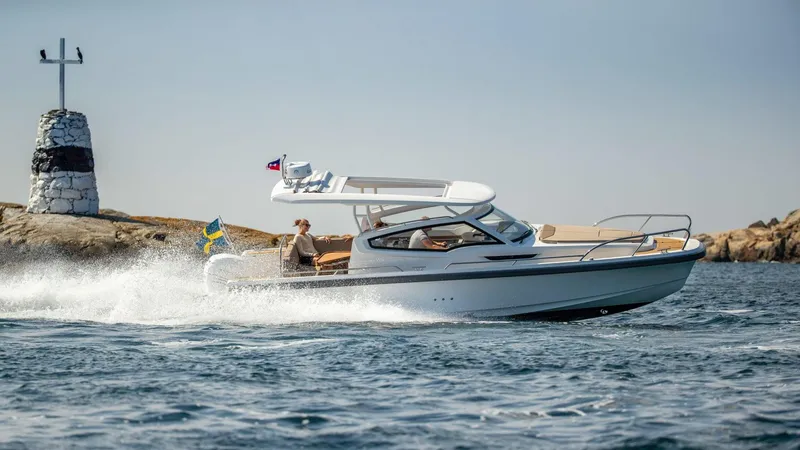The Image of 2023 Nimbus W9 boat cruising near rocky shoreline with lighthouse in background. - 0