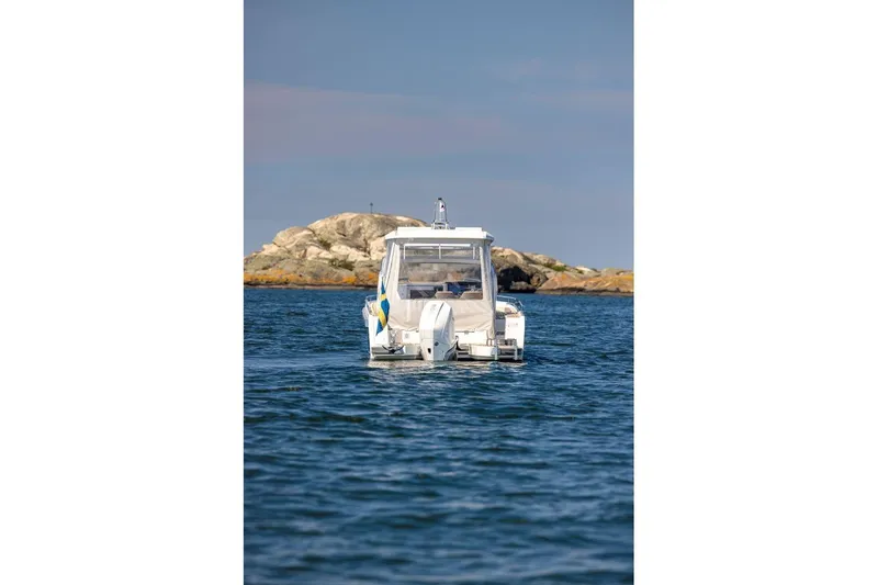 Slide: The Image of 2023 Nimbus W9 boat on water near rocky shoreline under clear sky. - 14