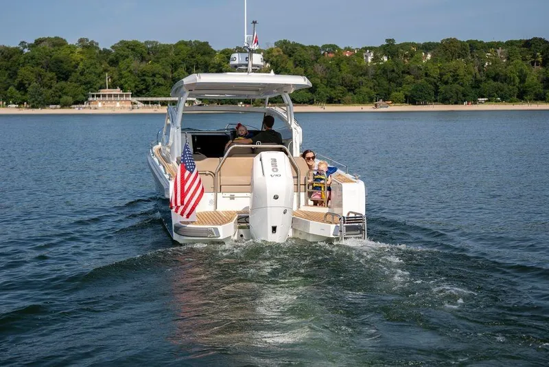 Slide: The Image of 2023 Nimbus W9 boat cruising on a lake with passengers, American flag displayed. - 20