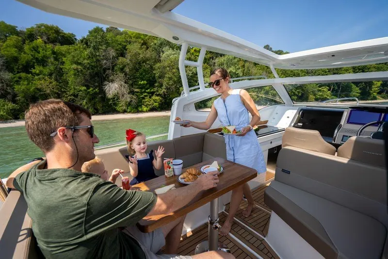 Slide: The Image of Family enjoying a meal on a 2023 Nimbus W9 boat, surrounded by lush greenery. - 22
