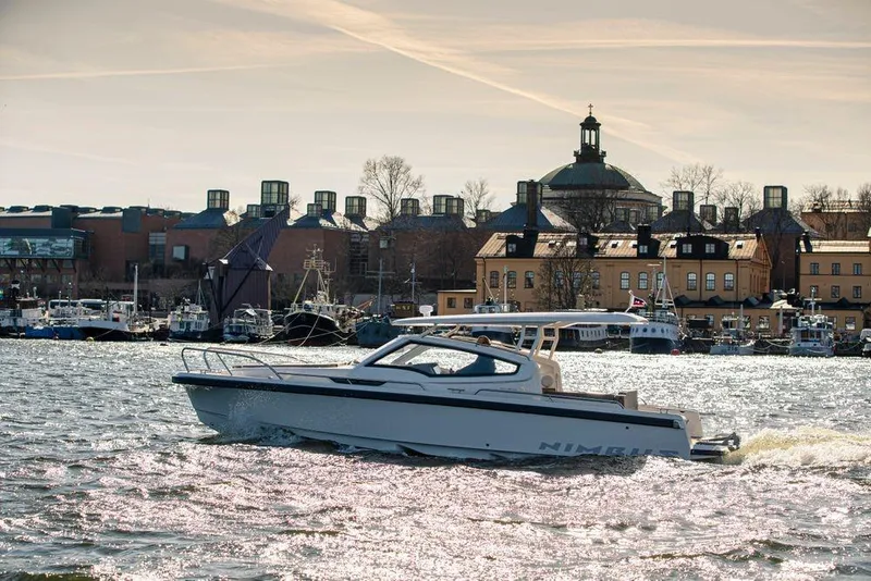 Slide: The Image of 2023 Nimbus W9 boat cruising on a scenic waterfront with historic buildings. - 7