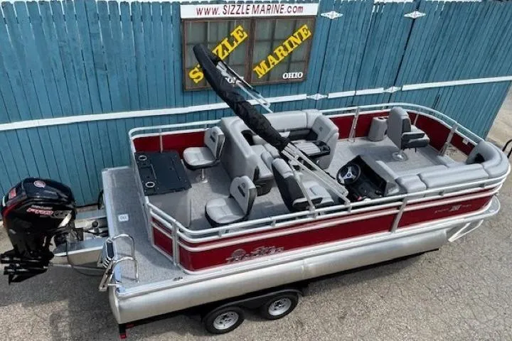 Slide: The Image of 2026 Sun Tracker SportFish 20 DLX pontoon boat with red and silver design, parked on trailer. - 0