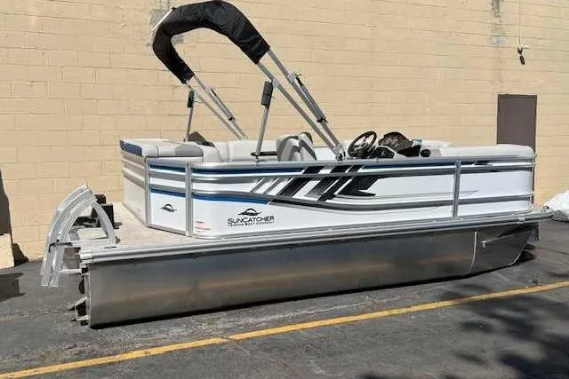 The Image of 2025 SunCatcher Select 18C pontoon boat with canopy, parked on pavement. - 0