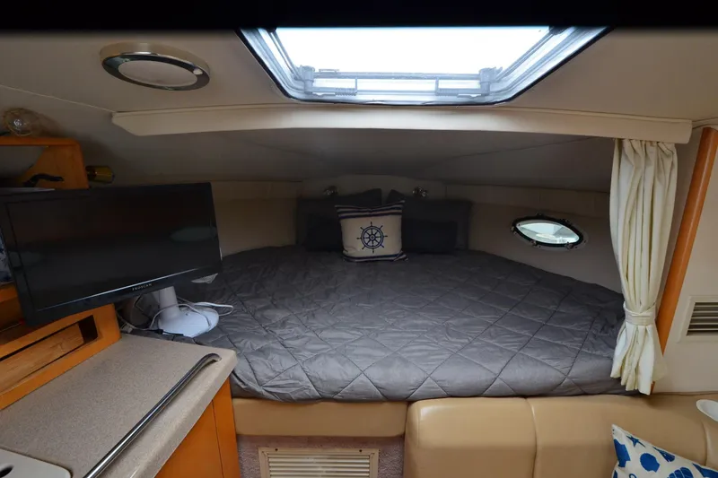 Slide: The Image of Interior cabin of 2000 Larson Cabrio 290 boat with bed, TV, and porthole window. - 14