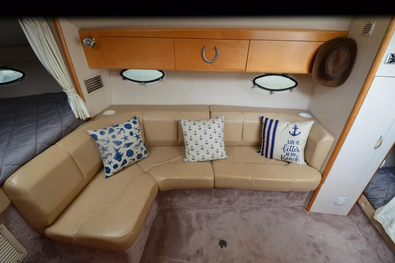 Slide: The Image of Interior of 2000 Larson Cabrio 290 boat with beige seating and nautical-themed pillows. - 15