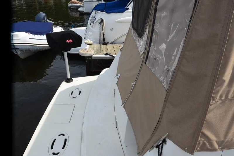 Slide: The Image of 2000 Larson Cabrio 290 boat docked with beige canopy and nearby vessels. - 6
