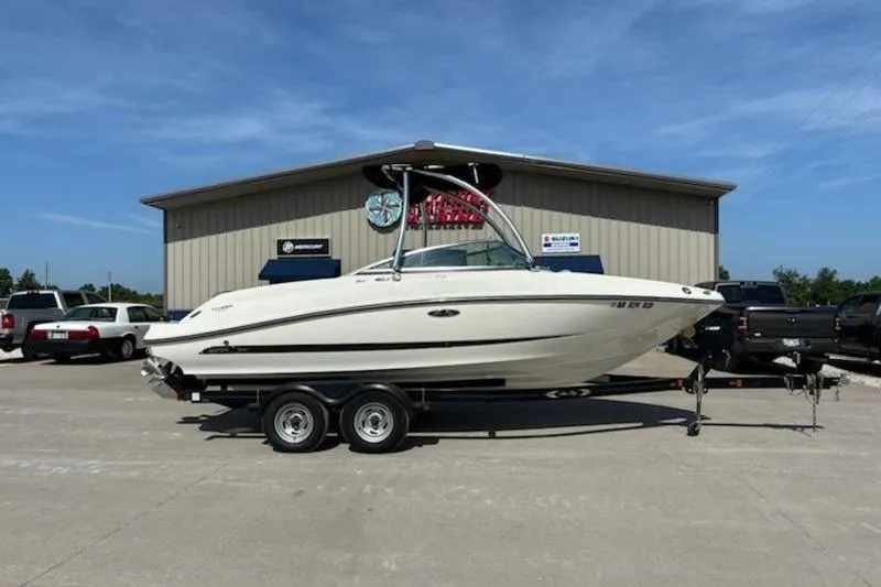 The Image of 2011 Sea Ray 210 SLX boat on trailer, parked outside a building under clear blue sky. - 1