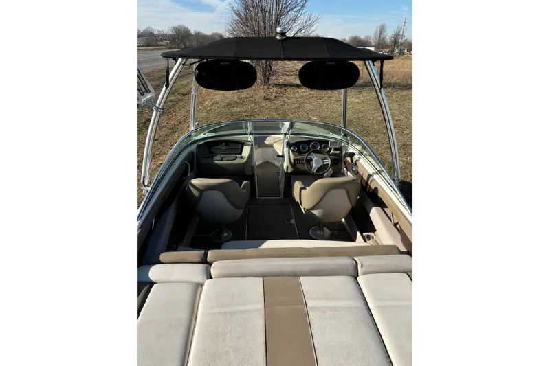 Slide: The Image of 2011 Sea Ray 210 SLX boat interior with seating and steering wheel, under a sunny sky. - 12