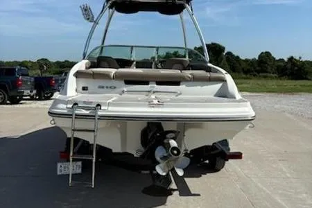 Slide: The Image of 2011 Sea Ray 210 SLX boat, rear view, parked on concrete, with ladder and propeller visible. - 3