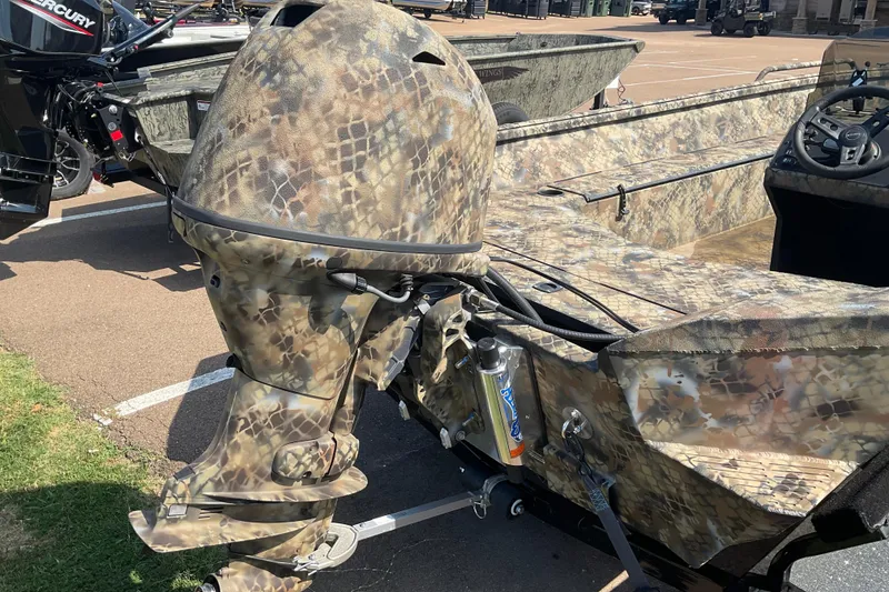 Slide: The Image of Camouflage-patterned 2025 Excel 1751 River Warrior boat with outboard motor in parking lot. - 2
