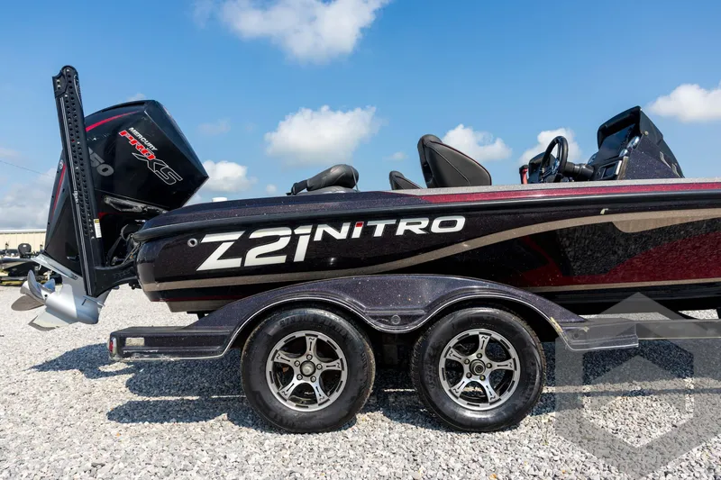 Slide: The Image of 2020 Nitro Z21 boat with dual axle trailer on gravel, under a clear blue sky. - 13