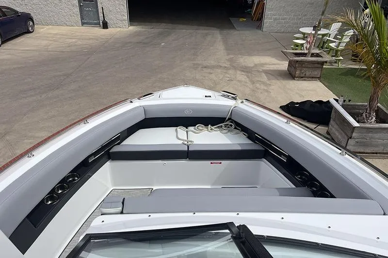 Slide: The Image of 2024 Cobalt A29 boat interior with gray seating and cup holders, docked outdoors. - 8