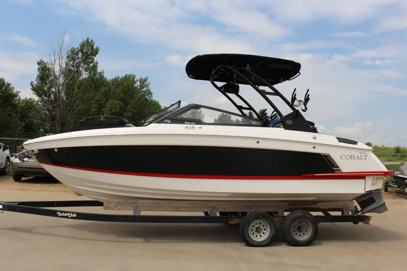 Slide: The Image of 2024 Cobalt R4 Surf boat on trailer, black and white design, parked outdoors. - 0