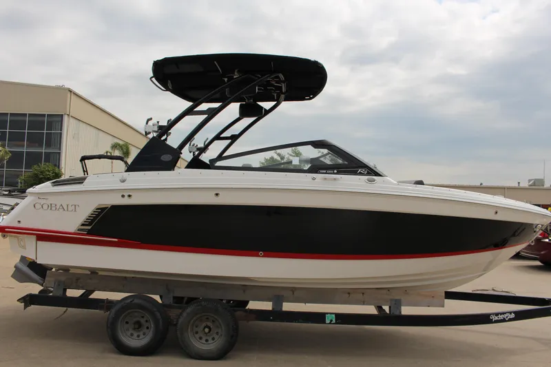 Slide: The Image of 2024 Cobalt R4 Surf boat on trailer, black and white design, outdoor setting. - 44