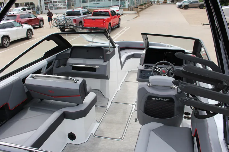 Slide: The Image of 2024 Cobalt R4 Surf boat interior with modern seating and steering wheel, parked outdoors. - 8