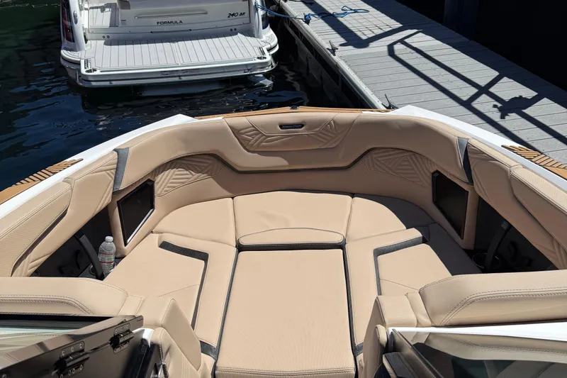 Slide: The Image of 2025 MasterCraft XStar 23 boat interior with beige seating, docked beside another boat. - 12