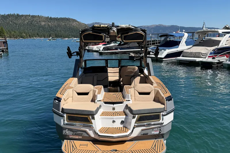 Slide: The Image of 2025 MasterCraft XStar 23 boat docked on a serene lake with scenic mountain backdrop. - 3