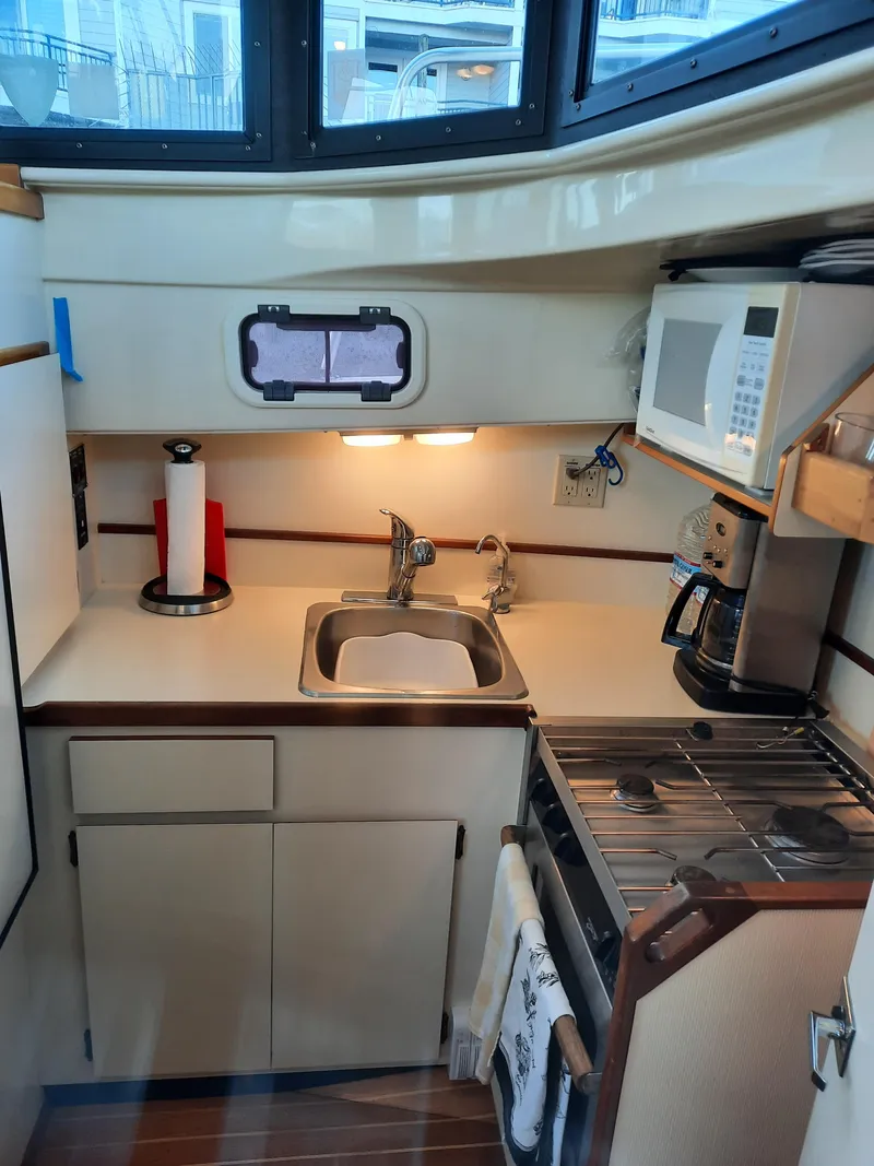 Slide: The Image of 2004 Camano Troll boat kitchen with sink, stove, microwave, and storage cabinets. - 21